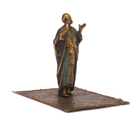 Figur forestillende orientalsk mand på tæppe i 
formessinget tin og dekoreret. H: 9,5cm. Base: 
9x11cm